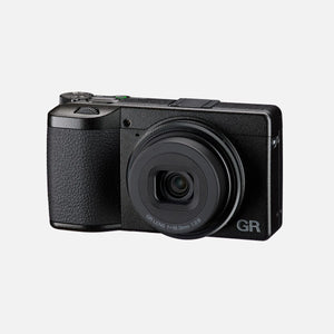 Ricoh GR IV di tre quarti dall'alto con l'obiettivo esteso, che mostra l'impugnatura in materiale goffrato e i comandi sul piano superiore