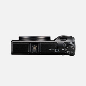 Ricoh GR IV vista dall'alto a fotocamera spenta: la slitta a contatto caldo, il pulsante di scatto, l'interruttore di accensione e la ghiera dei modi
