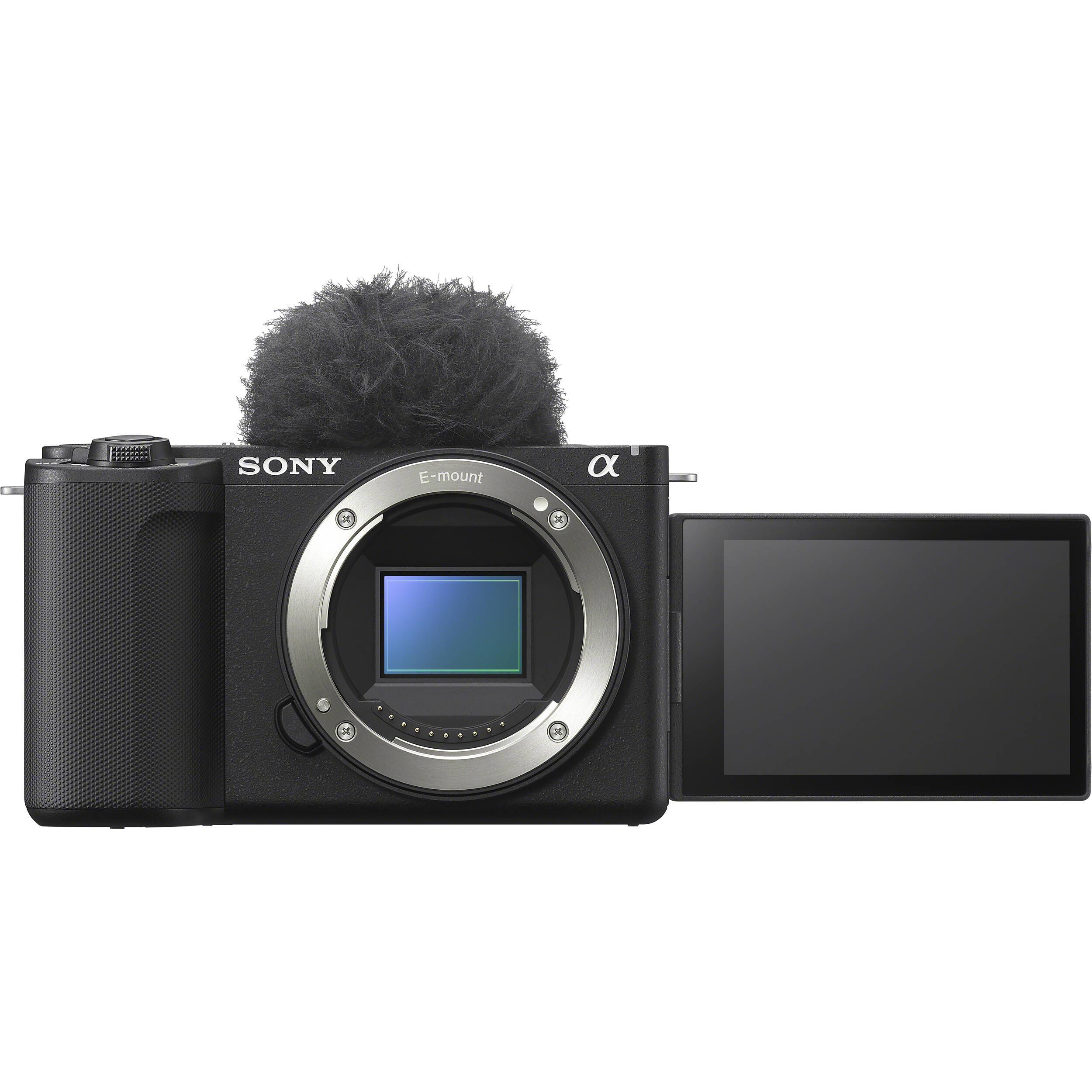 Fotocamera Sony ZV-E10 II nera solo corpo vista di fronte, senza obiettivo: l'innesto Sony E aperto con il sensore APS-C in vista, il paravento peloso montato sulla slitta e lo schermo aperto lateralmente