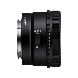 Sony FE 50mm F2.5 G di profilo dal lato dell'interruttore CLICK ON/OFF, quello che toglie gli scatti alla ghiera dei diaframmi per le riprese video: si vedono il marchio SONY sul barilotto, la flangia in metallo dell'innesto E-mount e la ghiera di messa a fuoco zigrinata