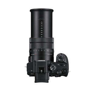 Sony RX10 V vista dall'alto con l'obiettivo esteso: la scala degli angoli di campo da 24 a 600 mm stampata sul barilotto, la ghiera dei diaframmi, la ghiera dei modi e la scritta RX10 V