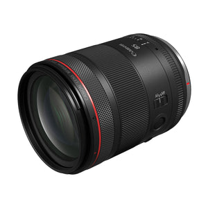 Canon RF 85mm F1.4 L VCM di tre quarti dal davanti, con la lente anteriore che riflette il verde del trattamento antiriflesso, il selettore AF/MF e il pulsante funzione programmabile