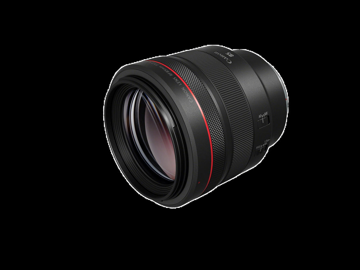 Canon RF 85mm F1.2 L USM di tre quarti dal davanti, con la lente frontale trattata, la ghiera di messa a fuoco zigrinata e i selettori sul fianco